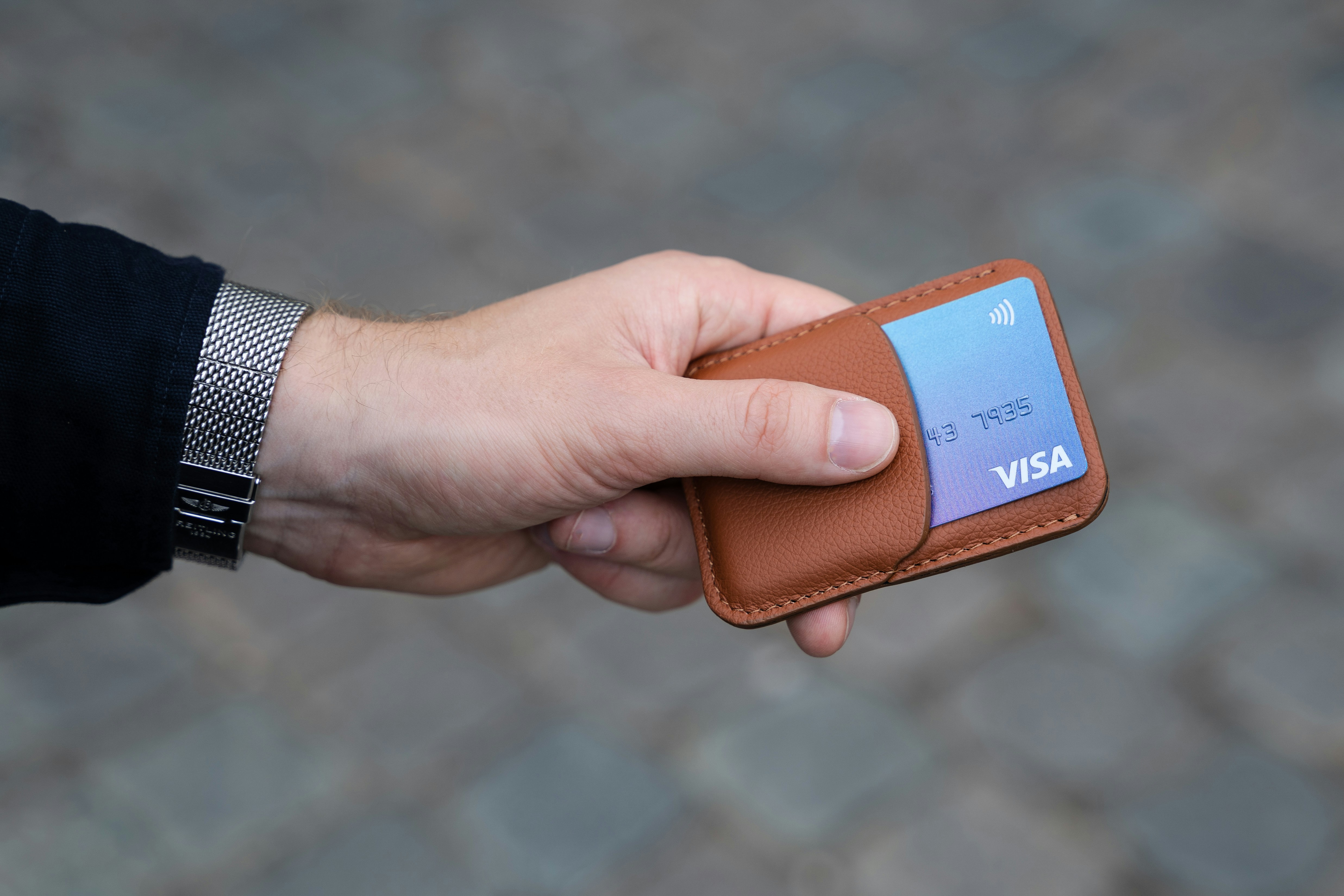 Photo of a brown card holder in a male hand.